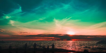 Silhouettes of people on the beach at sunset. City residents are enjoying a weekend by the sea....