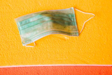 Medical face mask on yellow surface background. General personal protective equipment for use in...