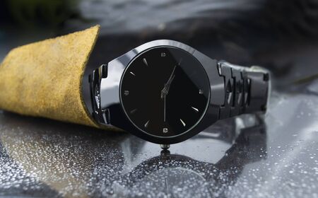 The Black wrist watch on the back glass surface is dark brown leatherの写真素材