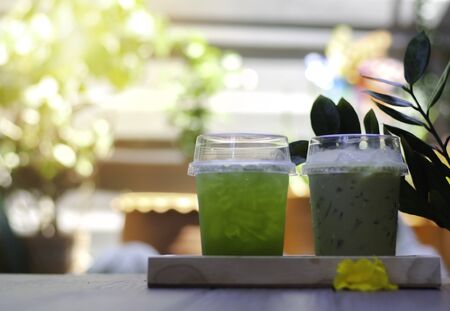 Two types of iced green tea placed in a wooden tray with a sunny garden background,Wait for someone...
