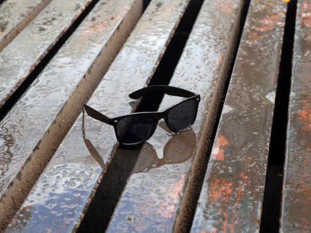 Wet Black Sunglasses On a Brown steel backgroundの写真素材