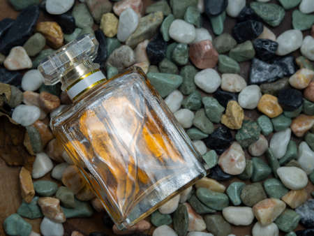 Brown perfume in square glass bottle Placed on a background with small stones,Is a mixture of essential oils or scent compounds, fixative (fixative) scent with solvent Used to make the human bodyの写真素材