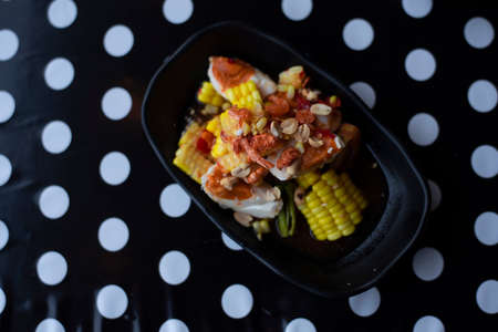 Thai papaya salad or Som Tum add salted eggs and yellow corn on a black background white polka dots