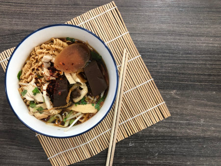 Noodles in a white bowl. On bamboo background. Dark brown table. There are ready-to-eat side dishes...