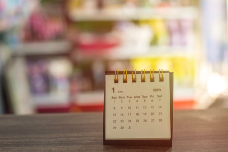 Calendar on the table, placed on the dark brown table In the background is a grocery store, blurred...