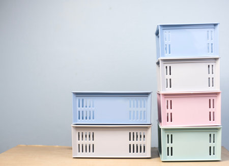 Plastic crate containing items, assorted colors, placed on a light brown floor. There is a light...