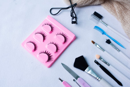 False eyelashes and beauty makeup equipment including makeup brushes of various sizes on a rough white backgroundの写真素材