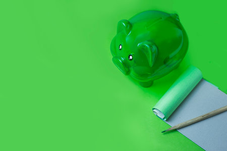 Green piggy bank Place it next to your income and expense notebook. The background is green as well. left side of frame There is space to put messages or ideasの写真素材