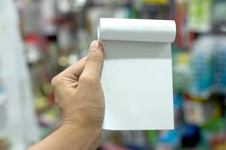 Empty notebook in hand At the back is a shop. There are many things to sell. But with a long distance blurred, unable to seeの写真素材