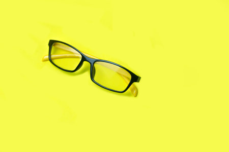 Clear glasses, yellow temples, black frames, placed on a bright yellow background, with a shoulder strap for putting messages. or creativityの写真素材