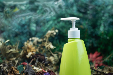 Green plastic pump bottle among the flowers and dark green dry leaves and sugar alternating withの写真素材