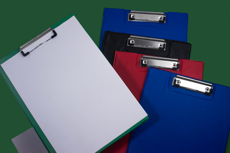 Clipboards, many pieces, assorted colors, clip paper, ready to use, dark green background on the backの写真素材