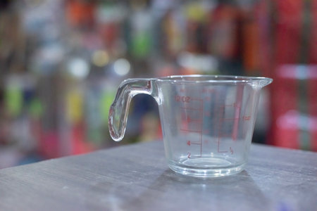 empty glass jar on a dark brown wooden table, behind which are many things.の写真素材