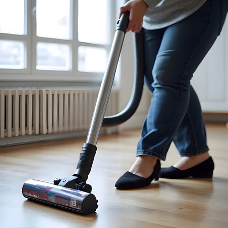 woman Cleaning Bedroom with Cordless Vacuum Cleaner in Sunlight,Woman Vacuuming Carpet in a Bright Bedroom with Sunlight and Dust Particlesの素材