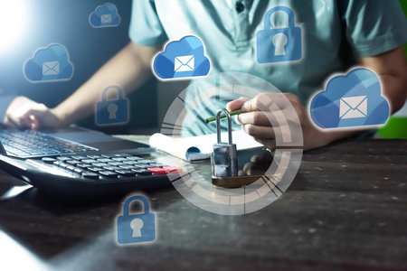 A person is seen working on a laptop and smartphone with a physical padlock and a glow of digital...