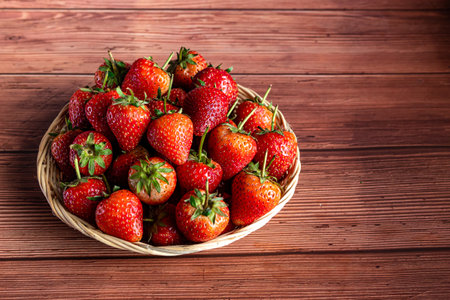 Strawberries in a wicker basket on a wooden background.の写真素材