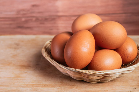 Fresh eggs in a basket on wooden background. Close-up.の写真素材