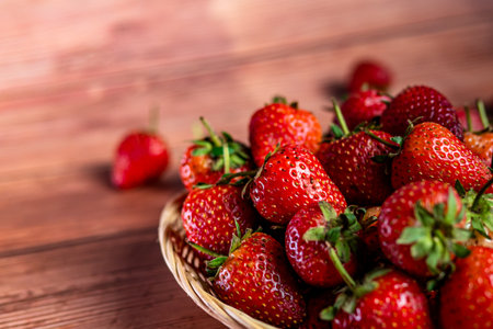 Strawberries in a wicker basket on a wooden background.の写真素材