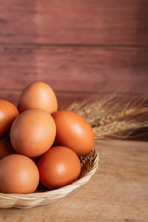 Eggs in a basket and ears of wheat on a wooden backgroundの写真素材