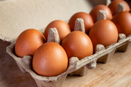 Fresh eggs in a cardboard box on a wooden background. Close-up.の写真素材
