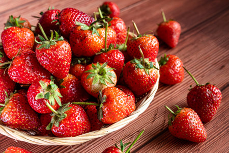 Strawberries in a wicker basket on a wooden background.の写真素材