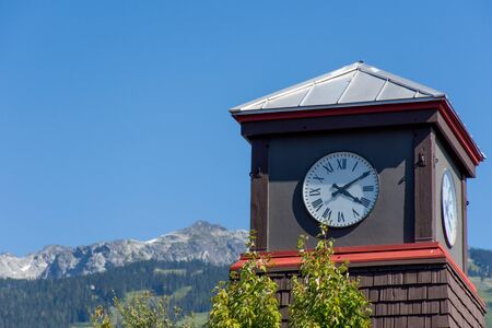 Roman Numeral Clock Tower with rocky mountains and blue sky in the background.の写真素材
