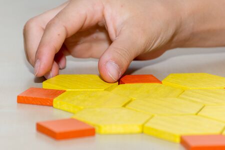 Tangram hexagon flower colored child geometric puzzle piece with childs hands  moving pieces side...