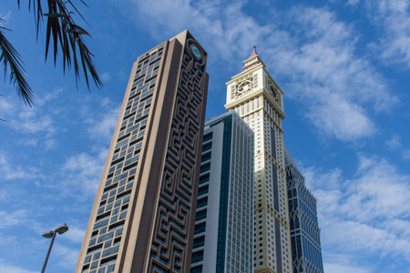 Dubai International Financial Centre (DIFC)  Iconic The Tower (clock) and Al Yaqoub Tower amid modern Dubai skyscrapers on blue sky