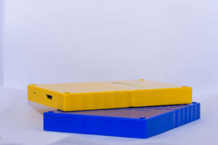 Yellow and blue portable usb hardrives stacked on isolated white background.の写真素材