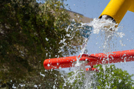 Summertime fun for the kids at the splash pad to play with water falling from bright colored yellow fountain to pool below.の写真素材