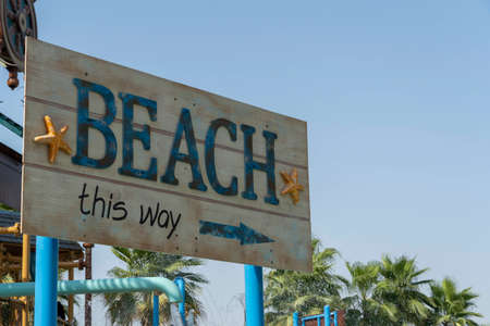 Tropical Beach this way directional sign with copy space on blue sky for vacation and summer conceptsの写真素材