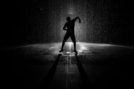 Rain room silhouette of a person dancing in the rain in black and white.の写真素材