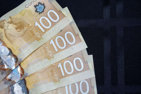 Close up of brown Canadian hundred (100) dollar bills with black backround and copy space.の写真素材