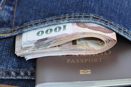 Thailand bank note and passport in jeans pocket.