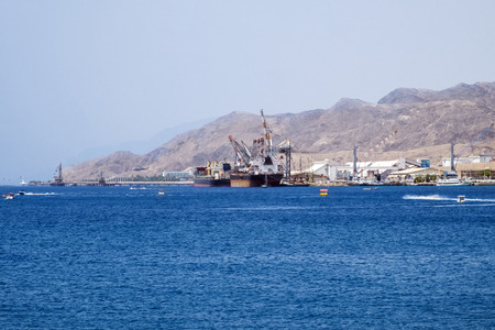 Cargo ships in the port of the Red Sea against the backdrop of the Eilat Mountains (Israel)