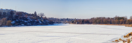 The frozen and snowy river Southern Bug and and in the distance a bridge and Temple of Blessed Xenia of Peterburg (Ukraine, Vinnitsa)の写真素材