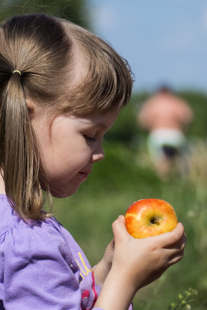 Little girl holding a ruddy appleの写真素材