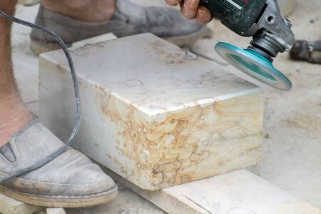 Angle grinder makes chamfer on antique travertineの写真素材