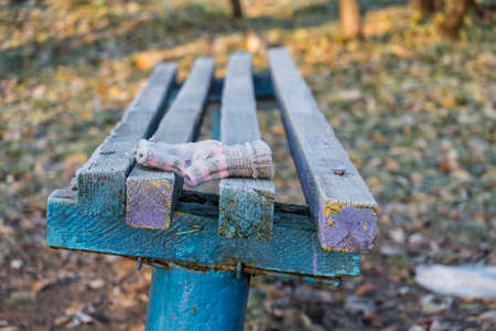 Lost knitted mitten lies on a wooden bench covered with frostの写真素材
