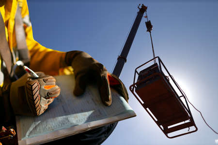Construction miner supervisor wearing  safety glove signing working at height working permit on open...