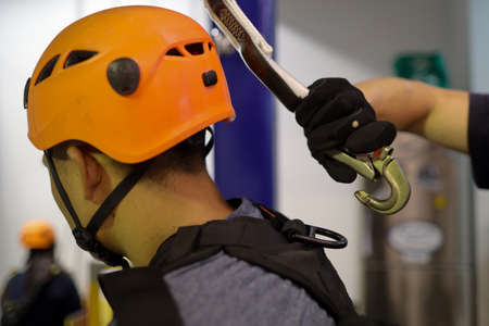 Closeup pic worker hand wearing black glove clipping an inertia reel safety hook into abseiler fall arrest body harness with together attached on lanyard shock absorber selt retracの写真素材