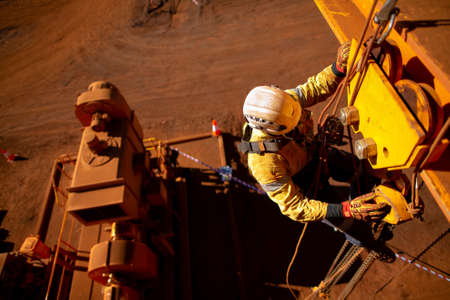Rope access worker wearing safety harness hard hat working at height descending on rope performing...