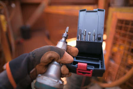 Safe workplaces male construction worker hand wearing a safety glove holding a die grinder with die set sizesの写真素材