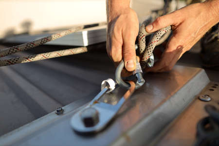 Rope access technician hand clipping rigging double rope and locking carabiner  fixed into permanent...