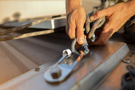 Rope access technician hand clipping rigging double rope and locking carabiner  fixed into permanent abseiling roof anchor point construction building site prior to used, Sydneyの写真素材