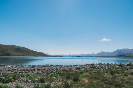 Lakeside with rock and blue sky and mountainの写真素材