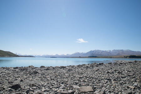 Lakeside with rock and blue sky and mountainの写真素材