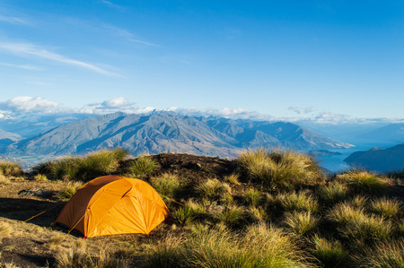 Orange tent in front of mountains; Roys Peak, Wanaka, New Zealandの写真素材