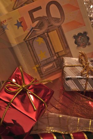 Christmas presents over a bunch of money (Euro bills) that represents how much important money is in today's consumist society, specially when Christmas comes.の写真素材