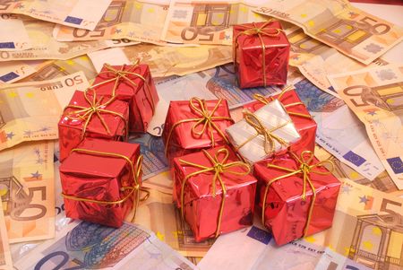 Christmas presents over a bunch of money (Euro bills) that represents how much important money is in today's consumist society, specially when Christmas comes.の写真素材